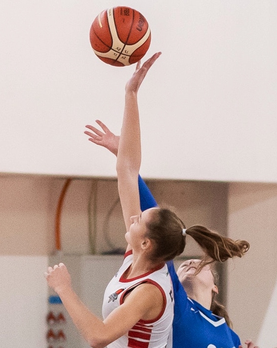 women reach for basketball